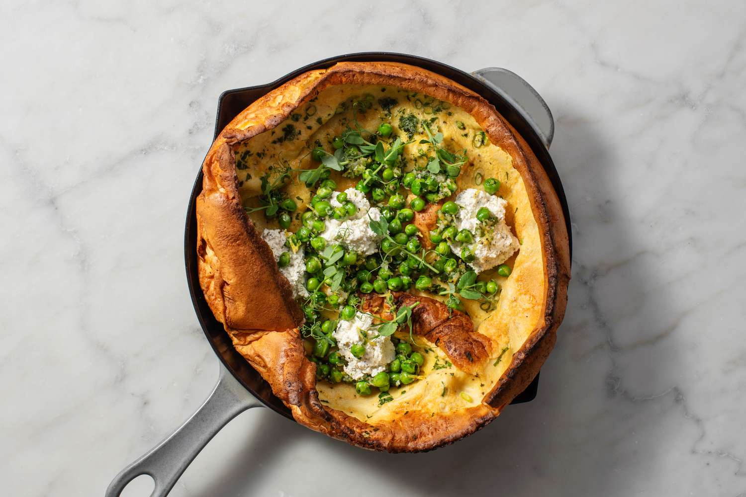 Un Dutch Baby au Boursin et petits pois garni de persil et de pousses de petits pois