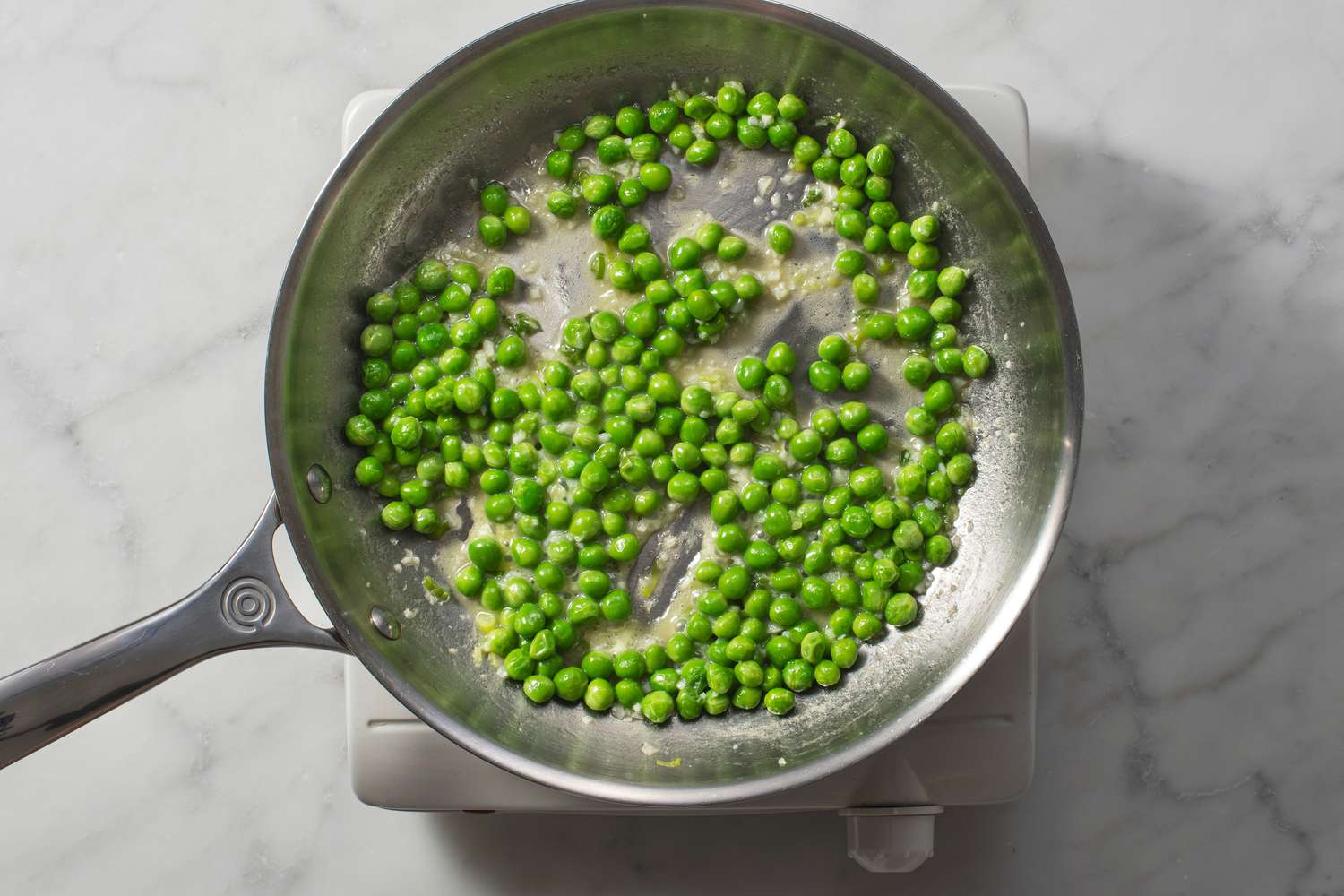 Eau ajoutée dans la poêle de petits pois cuisant